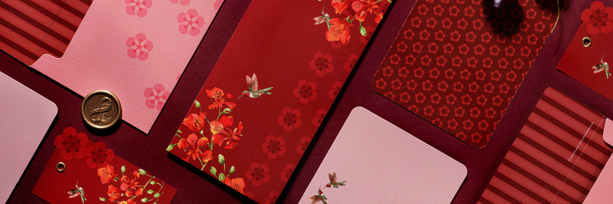 Blossom Notes money envelopes and cards on a deep maroon backdrop