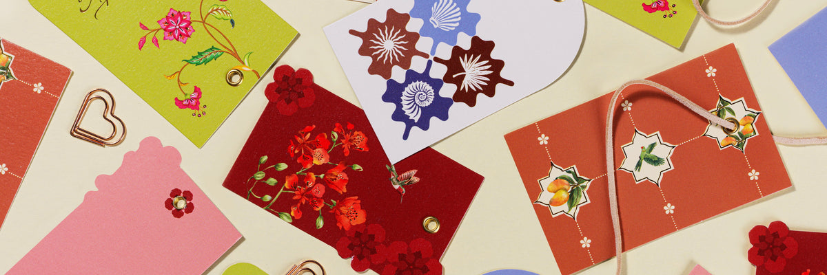 CohesiveNow gift tags in all four designs, scattered on cream